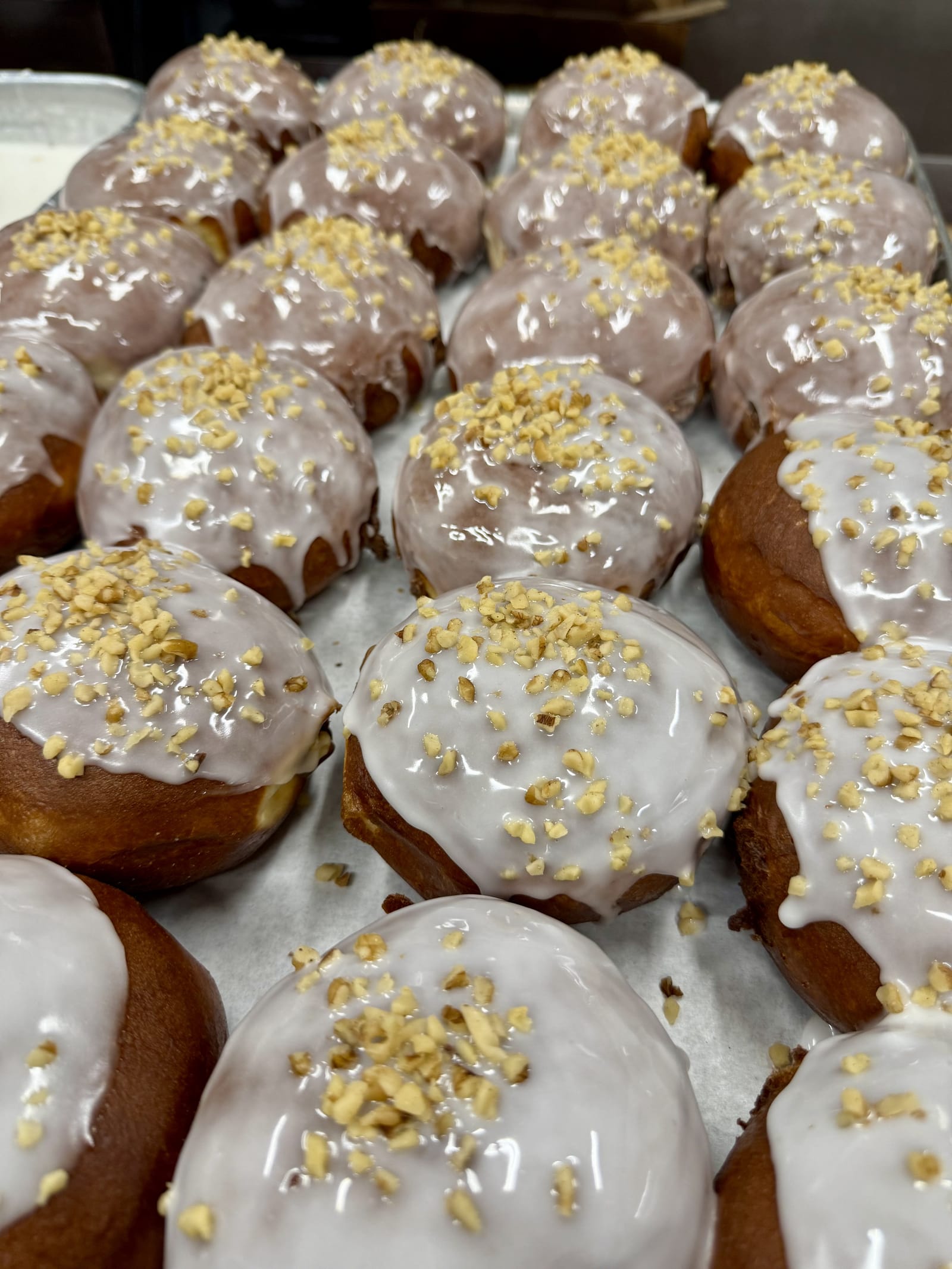 Glazed pączki sprinkled with chopped nuts