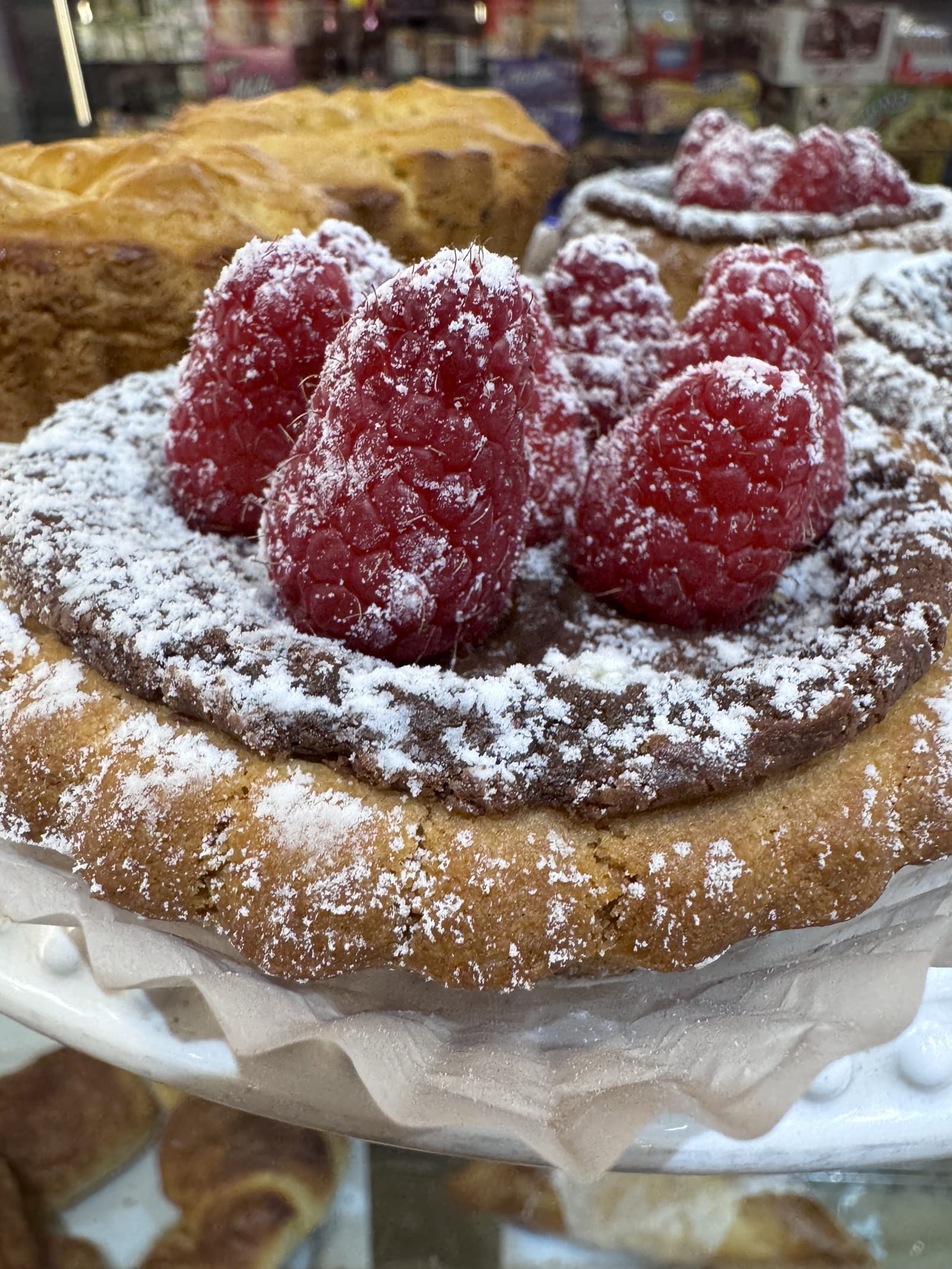 A tart topped with fresh raspberries and powdered sugar